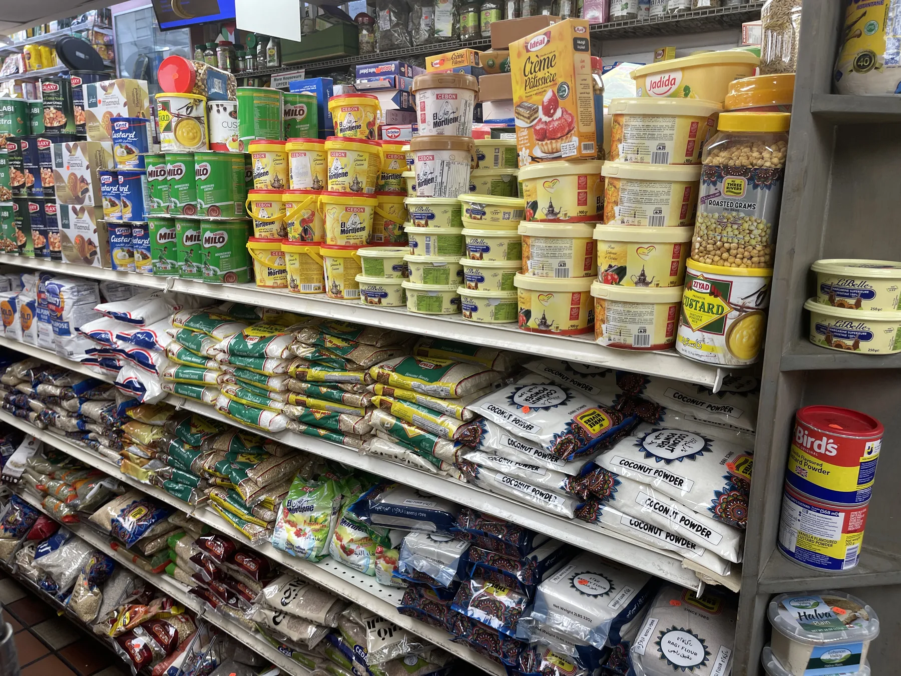 Pantry shelves stacked with coconut powder, custard, dried goods and pulses at Makkah Market in West Philadelphia