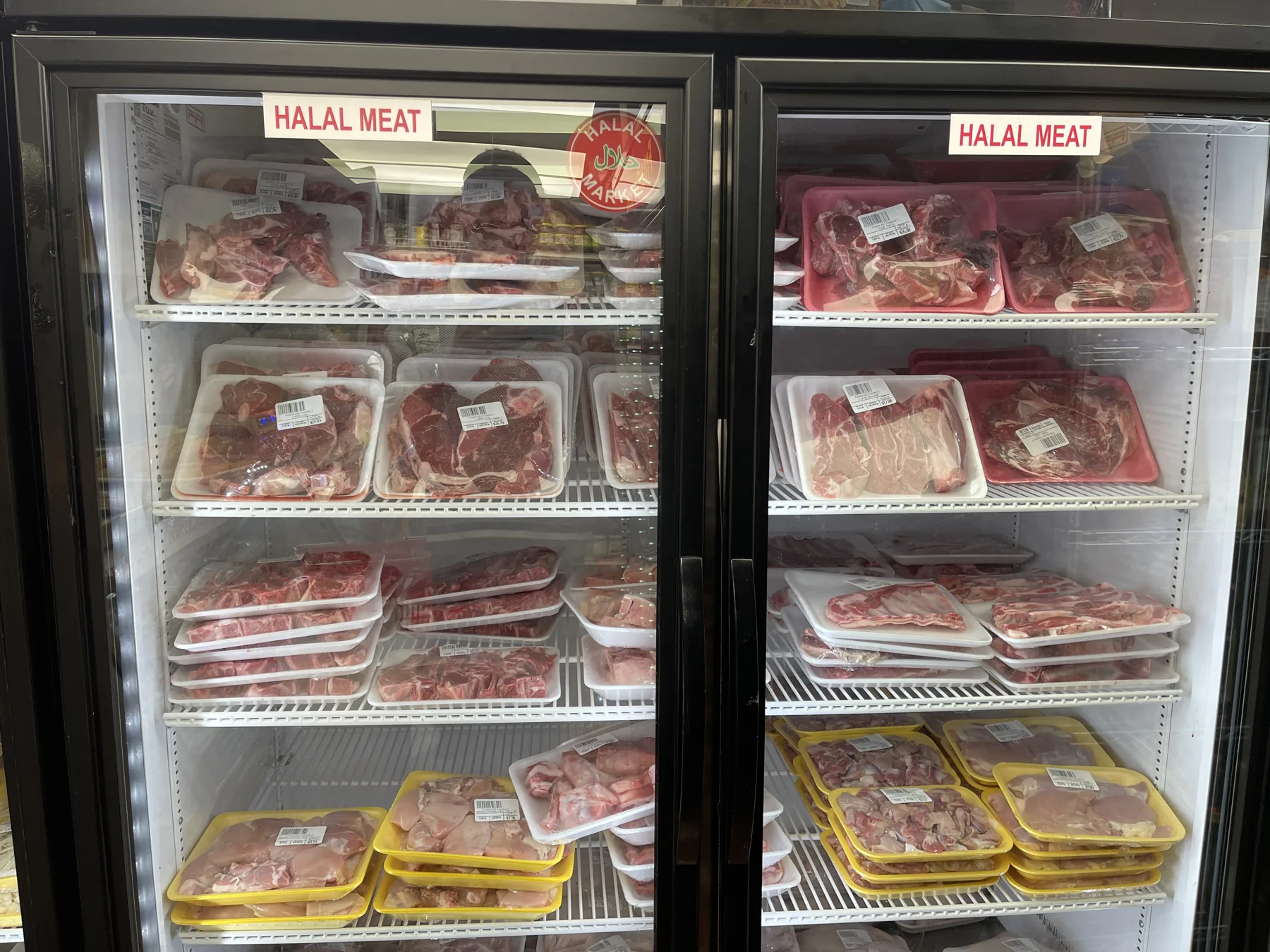 Second halal meat case at Makkah Market — packaged trays of fresh halal cuts in West Philadelphia